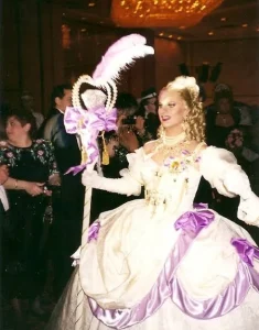 A gay man dressed ina ball gown, white with violet accents